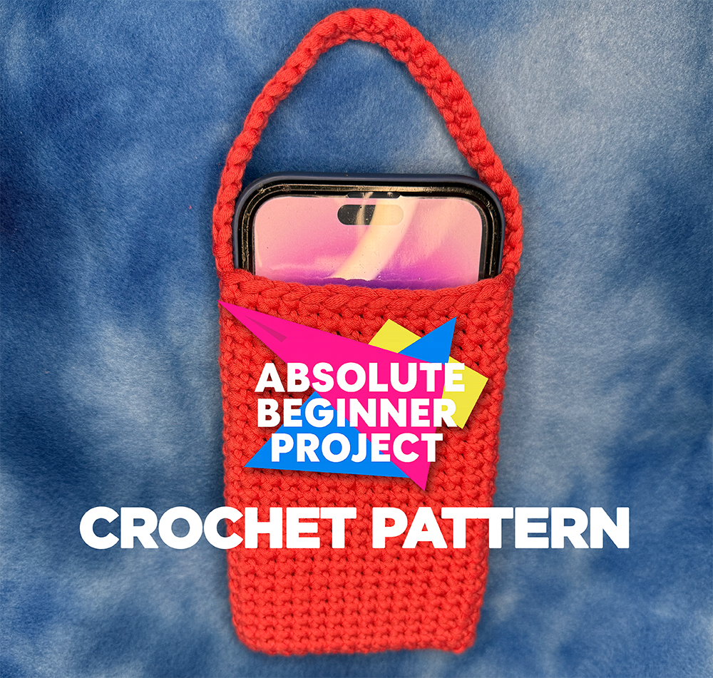 Red crochet phone tote with a handle holding a smartphone against a soft blue background. Text on image reads “Absolute Beginner Project – Crochet Pattern.” Image for Electric Eye Crochet free beginner pattern tutorial.